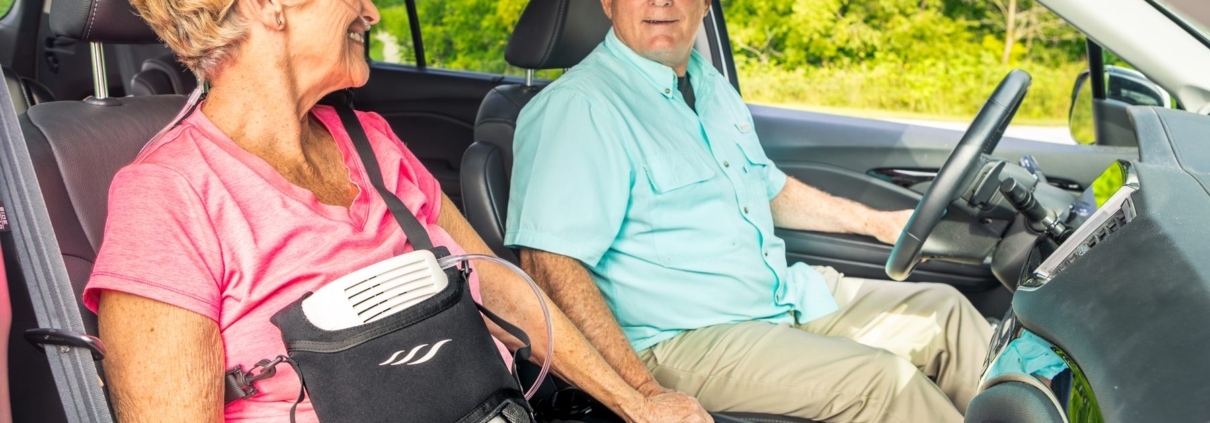 Woman using a portable oxygen concentrator in a carry bag while riding in a car