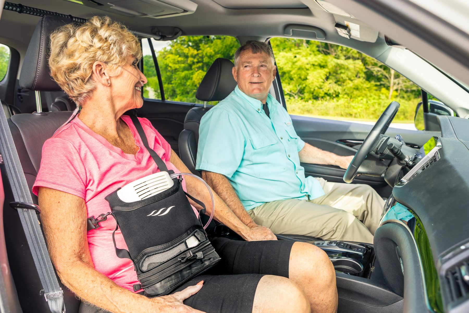 Woman using a portable oxygen concentrator in a carry bag while riding in a car